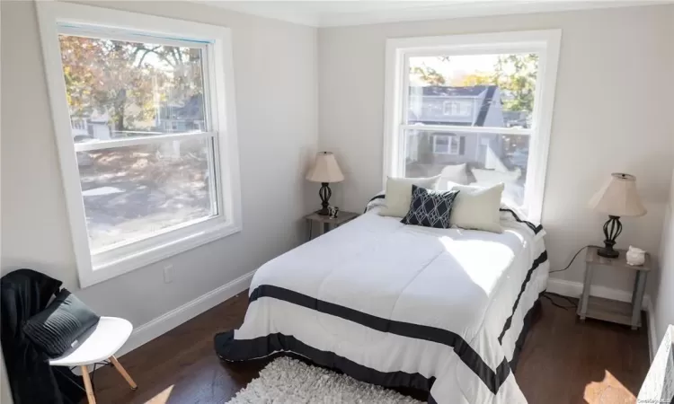 Bedroom with dark hardwood / wood-style flooring and ornamental molding