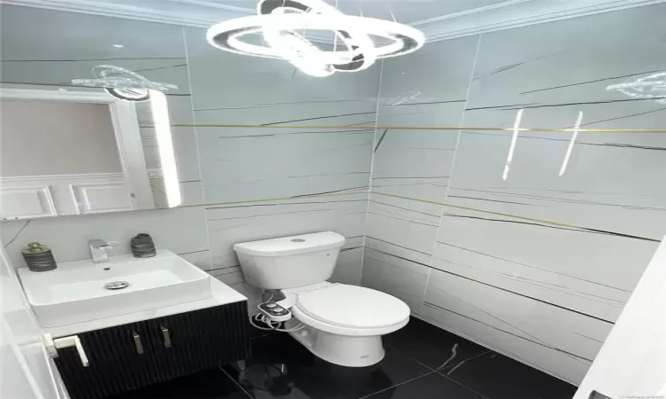 Bathroom with tile patterned floors, vanity, toilet, and crown molding