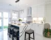 Kitchen featuring white cabinets, pendant lighting, and wall chimney range hood