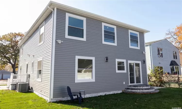 Rear view of property featuring a lawn and central air condition unit