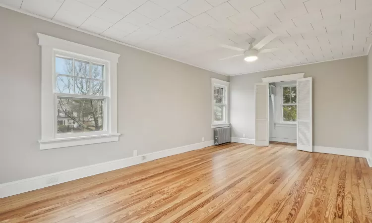 Primary Bedroom with light hardwood / wood-style flooring, radiator, ornamental molding, and ceiling fan