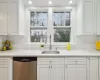 Kitchen with white cabinetry, dishwasher, sink, tasteful backsplash, and plenty of natural light