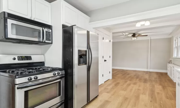 Kitchen featuring white cabinetry, ceiling fan, stainless steel appliances, beamed ceiling, and light hardwood / wood-style floors