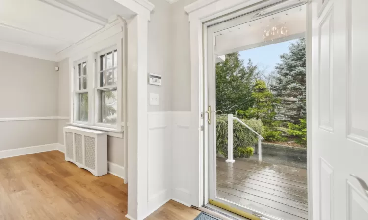 Doorway to outside featuring light hardwood / wood-style floors, crown molding, and radiator