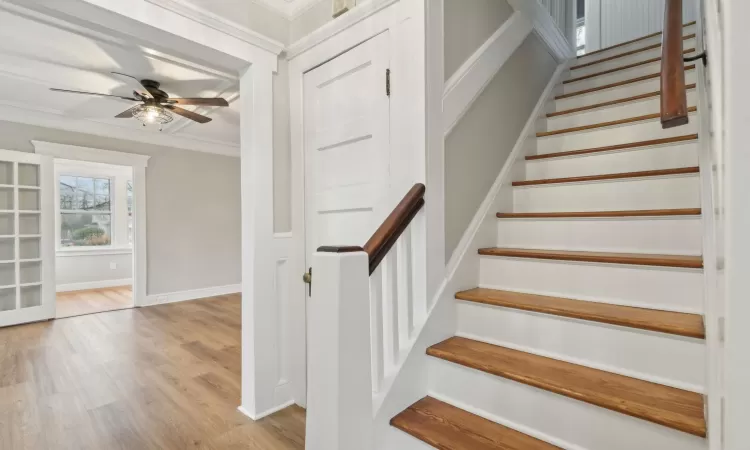 Stairway with ceiling fan, crown molding, and hardwood / wood-style floors