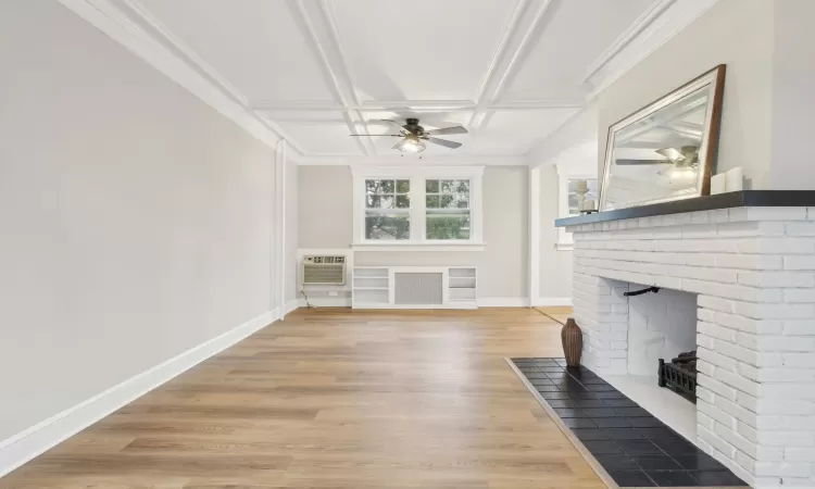 Unfurnished living room with coffered ceiling, an AC wall unit, a brick fireplace, ceiling fan, and wood-type flooring