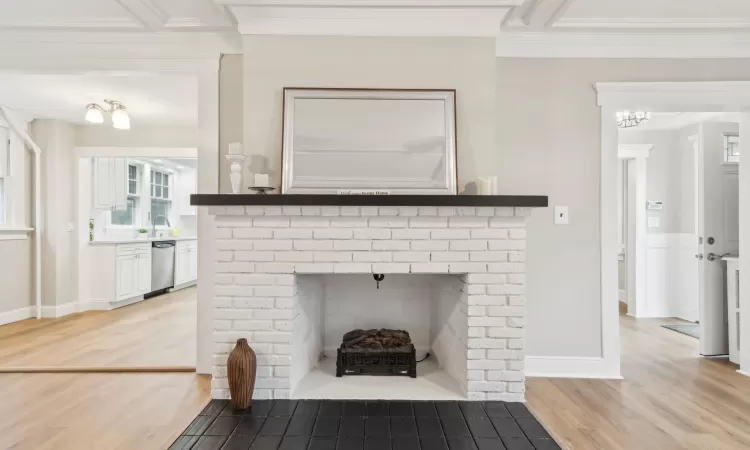 Room details with crown molding, dishwasher, wood-type flooring, and a brick fireplace