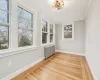 Sun room featuring plenty of natural light, wood-type flooring, radiator heating unit, and ornamental molding