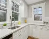 Kitchen featuring white cabinets, backsplash, dishwasher, and sink