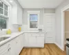 Kitchen with tasteful backsplash, plenty of natural light, white cabinets, and light hardwood / wood-style flooring