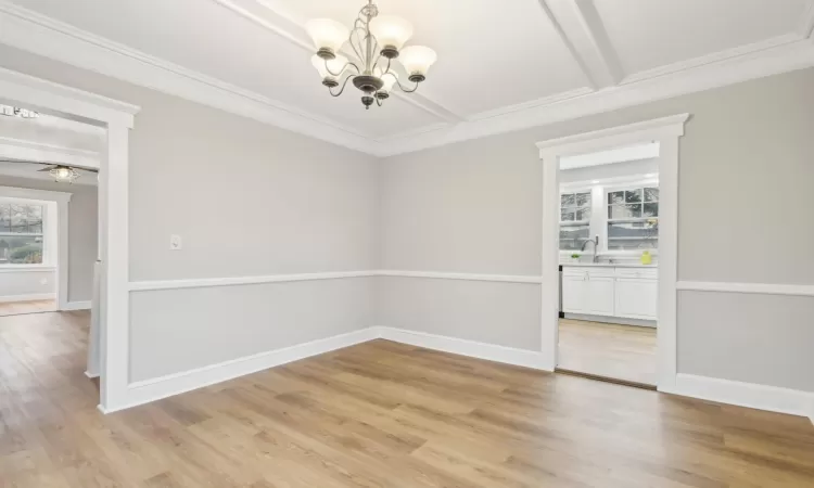 Dining room featuring ceiling fan with notable chandelier, crown molding, sink, light wood-type flooring, and beam ceiling