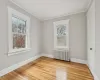 Bedroom with light hardwood / wood-style floors, radiator heating unit, and crown molding