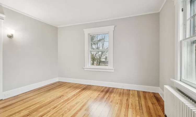 Bedroom with hardwood / wood-style flooring, crown molding, and radiator