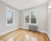 Bedroom with radiator heating unit, a healthy amount of sunlight, and hardwood / wood-style flooring