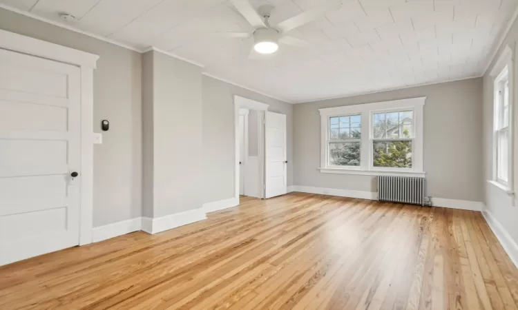 Primary Bedroom with ceiling fan, crown molding, radiator, and light hardwood / wood-style flooring