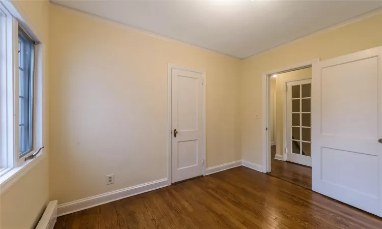 Spare room featuring a baseboard radiator, crown molding, and dark wood-type flooring