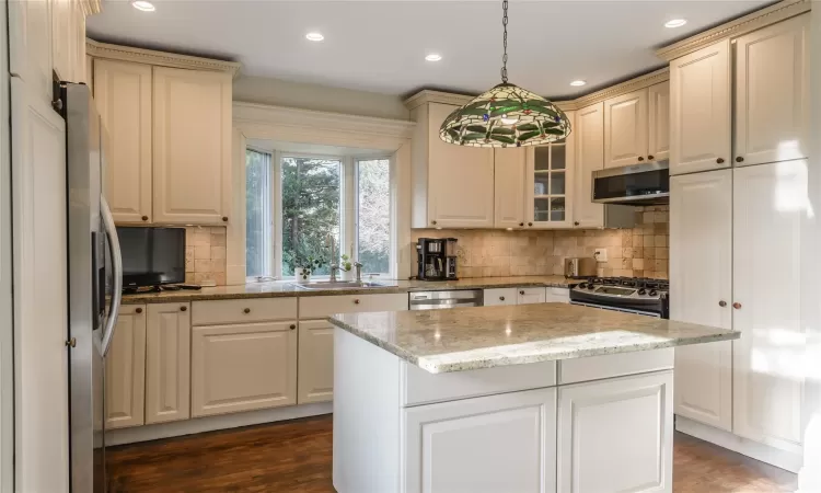 Kitchen with stainless steel appliances hanging light fixtures, decorative backsplash, a kitchen island, and appliances with stainless steel finishes