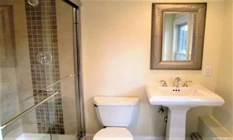 Bathroom featuring toilet and a shower with shower door