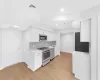 Kitchen with backsplash, white cabinets, sink, light wood-type flooring, and appliances with stainless steel finishes