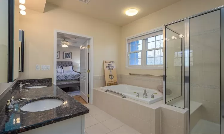 Primary Bathroom featuring tile patterned floors, ceiling fan, shower with separate bathtub, and vanity