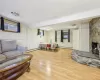 Living room with a fireplace, light wood-type flooring, a baseboard heating unit, and wood walls