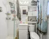 Bathroom with toilet, a tile shower, decorative backsplash, and vanity