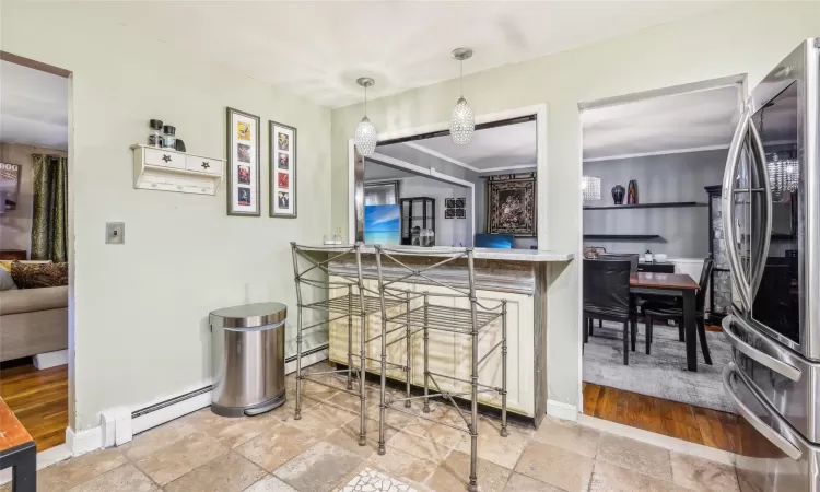 Kitchen featuring stainless steel fridge with ice dispenser, a baseboard radiator, and pendant lighting