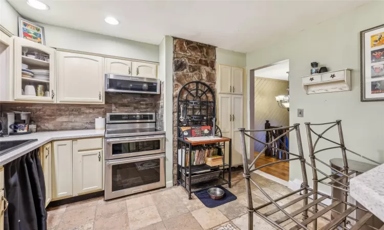 Kitchen with backsplash, stainless steel appliances, a notable chandelier, and sink