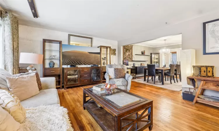 Living room with hardwood / wood-style flooring, a notable chandelier, and wood walls