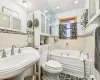 Bathroom featuring sink, tile patterned flooring, toilet, a bathtub, and tile walls