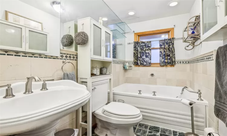 Bathroom featuring sink, tile patterned flooring, toilet, a bathtub, and tile walls