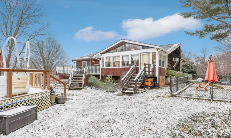 Snow covered back of property featuring a sunroom