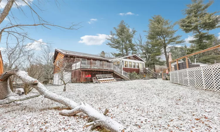 Snow covered back of property featuring a wooden deck