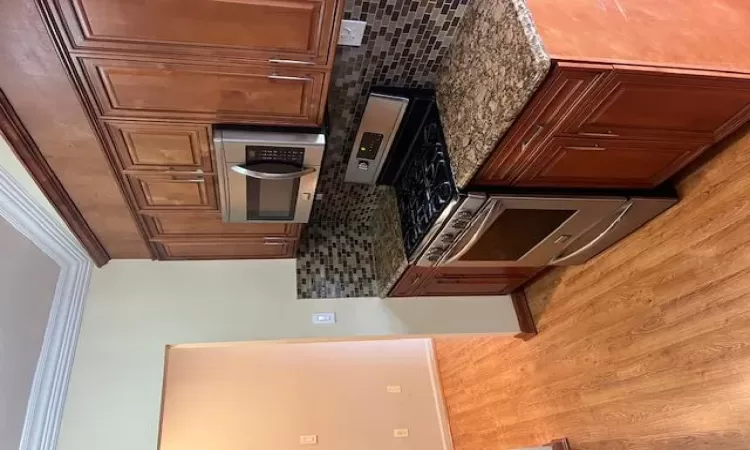 Kitchen featuring decorative backsplash, crown molding, stainless steel range, and dark stone counters