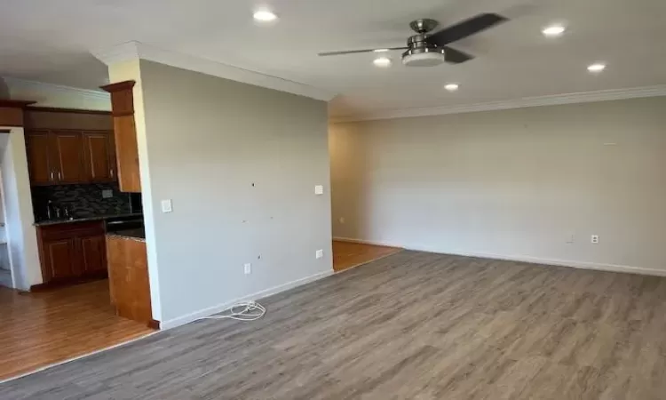 Unfurnished living room with hardwood / wood-style floors and crown molding