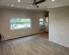 Unfurnished room with a wall mounted air conditioner, ceiling fan, ornamental molding, baseboard heating, and light hardwood / wood-style floors