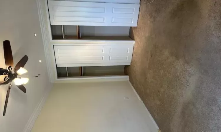 Unfurnished bedroom with carpet, two closets, ceiling fan, and crown molding