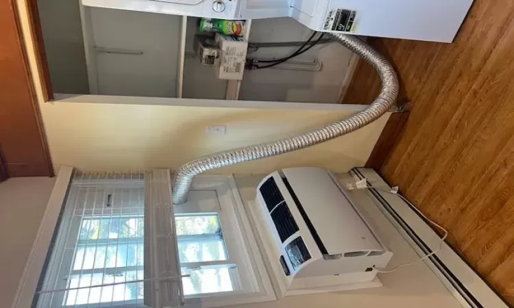 Interior details with an AC wall unit, hardwood / wood-style floors, and a baseboard heating unit