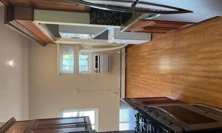 Kitchen featuring dishwasher, stacked washer and clothes dryer, decorative backsplash, dark stone countertops, and a wall mounted AC