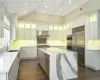 Kitchen featuring light stone countertops, stainless steel built in refrigerator, extractor fan, white cabinets, and a kitchen island. FOR MARKETING PURPOSES ONLY.