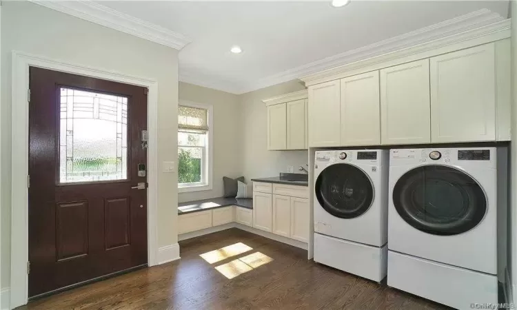 Laundry area with washer and dryer, ornamental molding, dark wood-type flooring, and cabinets. FOR MARKETING PURPOSES ONLY.