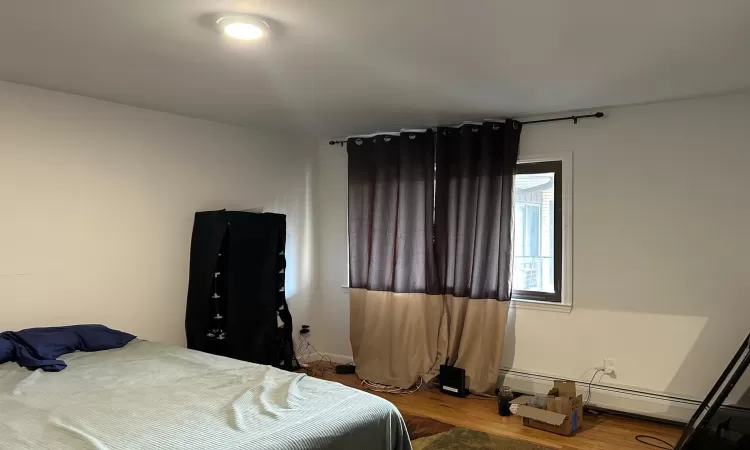 Bedroom with hardwood / wood-style flooring and a baseboard radiator