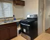 Kitchen featuring dark brown cabinets, sink, light tile patterned floors, and black gas range oven