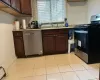 Kitchen with dishwasher, black stove, a baseboard radiator, dark brown cabinets, and light tile patterned flooring