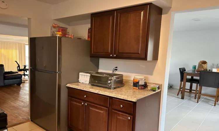 Kitchen with stainless steel fridge, dark brown cabinetry, and light hardwood / wood-style floors