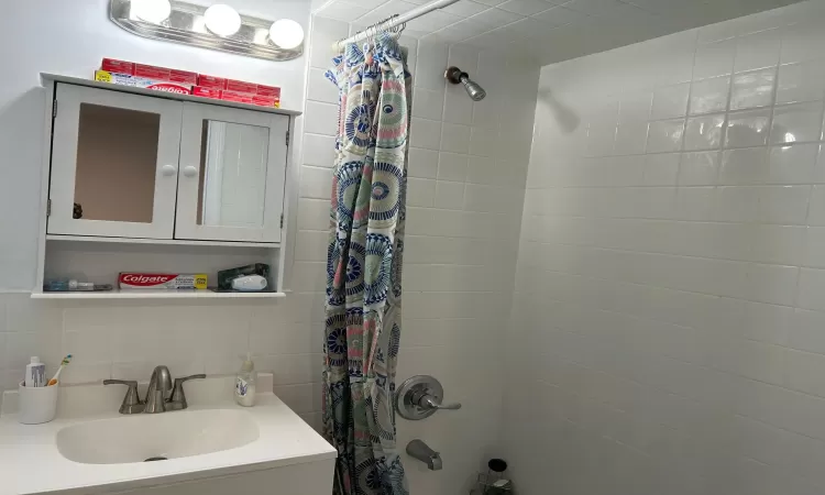 Bathroom with decorative backsplash, shower / bathtub combination with curtain, and vanity