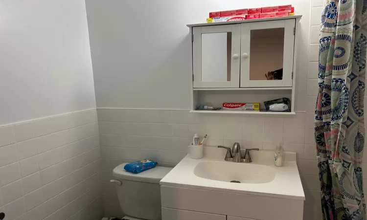 Bathroom with vanity, toilet, and tile walls