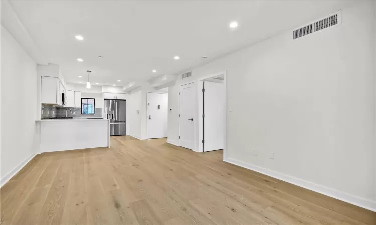 Unfurnished living room with light hardwood / wood-style floors and sink