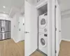 Laundry room with light hardwood / wood-style flooring and stacked washer / drying machine