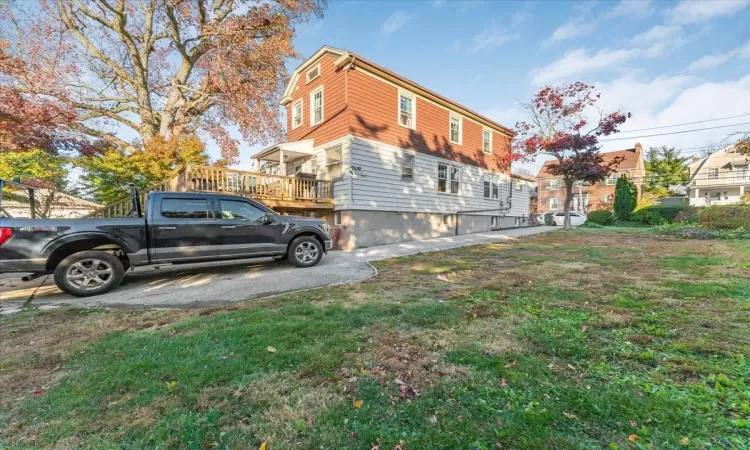 View of side of home featuring a yard and a wooden deck